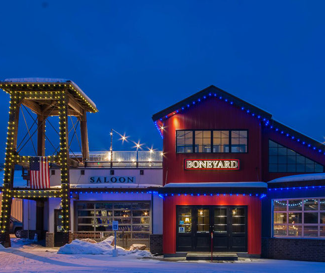 Evening photo of the exterior of Boneyard Saloon and Kitchen taken in the evening with snow on the eaves. 1251 Kearns Blvd in Park City, Utah